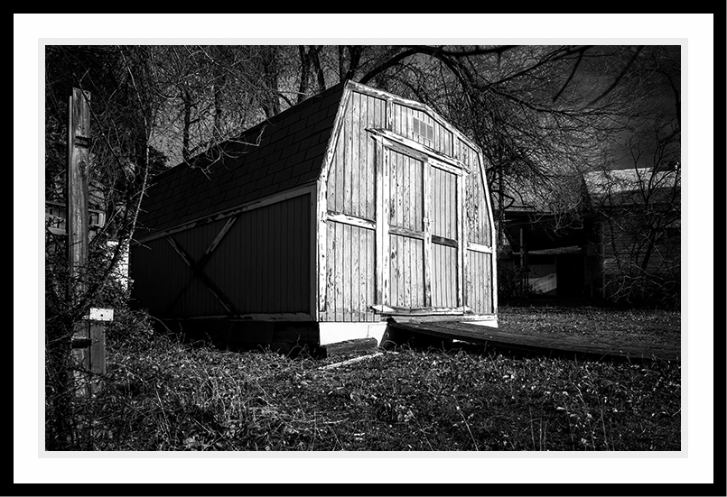 A shed sitting in a yard awaiting the approaching storm.